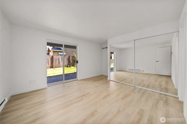 unfurnished bedroom with wood finished floors, access to outside, a closet, baseboard heating, and baseboards