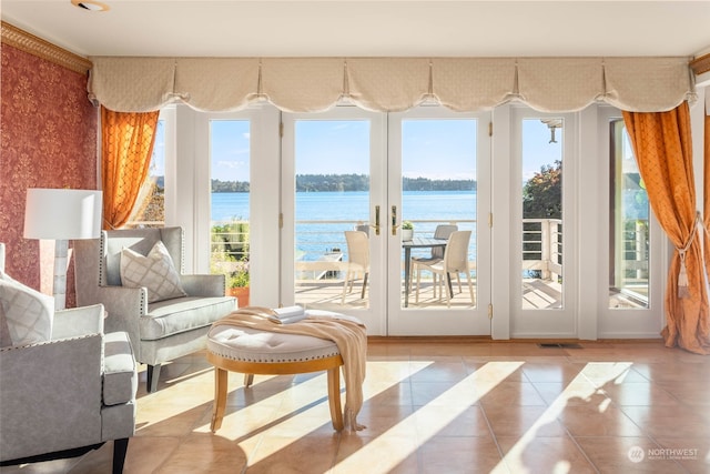 living room featuring a water view, light tile patterned floors, and french doors