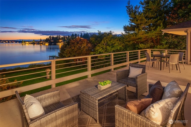 patio terrace at dusk featuring a water view and an outdoor living space