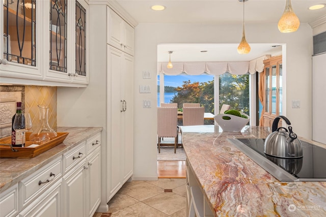 kitchen featuring white cabinetry, light stone countertops, and decorative light fixtures