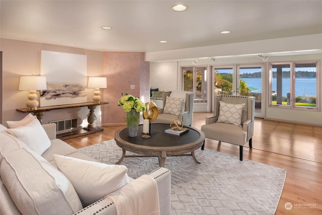 living room featuring light hardwood / wood-style flooring and a water view