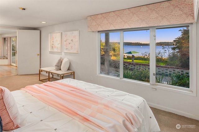 carpeted bedroom featuring multiple windows and a water view