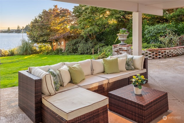 patio terrace at dusk featuring an outdoor hangout area, a water view, and a yard