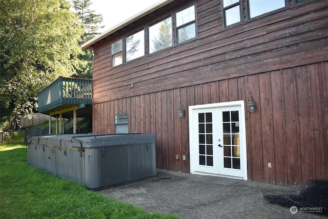 view of side of home featuring french doors, a balcony, and a hot tub