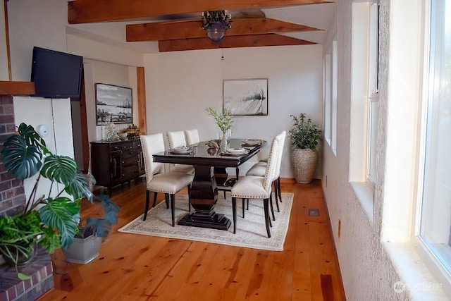 dining area featuring beamed ceiling and wood-type flooring