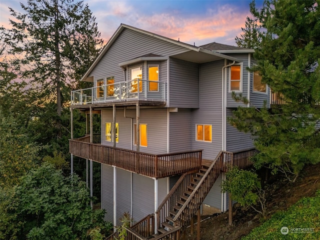 back house at dusk featuring a wooden deck