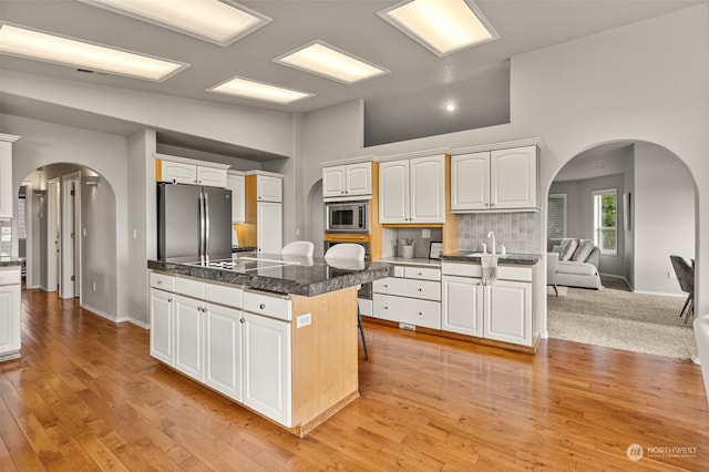 kitchen with white cabinets, a kitchen island, appliances with stainless steel finishes, and light hardwood / wood-style flooring