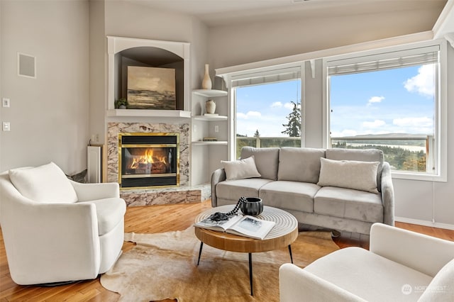 living room with hardwood / wood-style flooring, lofted ceiling, a high end fireplace, and plenty of natural light