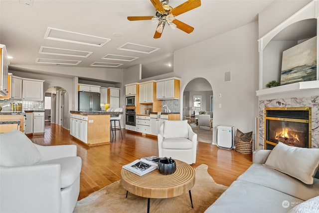 living room with hardwood / wood-style floors, ceiling fan, a premium fireplace, and sink