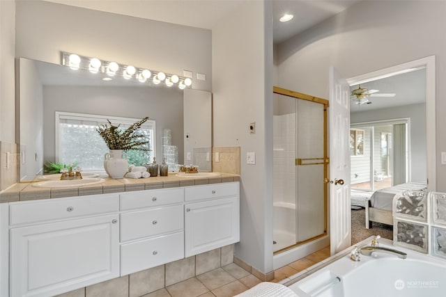 bathroom with plus walk in shower, vanity, ceiling fan, and a healthy amount of sunlight