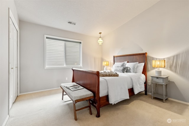 bedroom featuring a closet, light colored carpet, and a textured ceiling