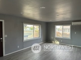 spare room featuring an AC wall unit and hardwood / wood-style floors