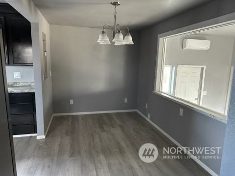 unfurnished dining area with a wall mounted air conditioner, an inviting chandelier, and dark hardwood / wood-style flooring