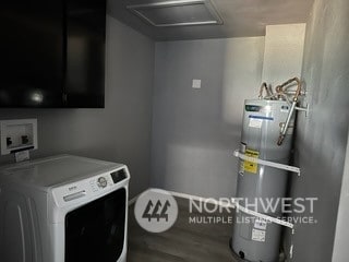 washroom with cabinets, strapped water heater, wood-type flooring, and washer / clothes dryer