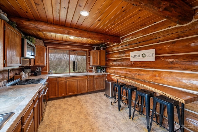 kitchen with wood ceiling, beam ceiling, tile counters, sink, and rustic walls