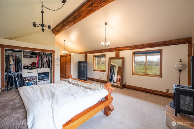 carpeted bedroom with vaulted ceiling with beams, a notable chandelier, a closet, and a wood stove