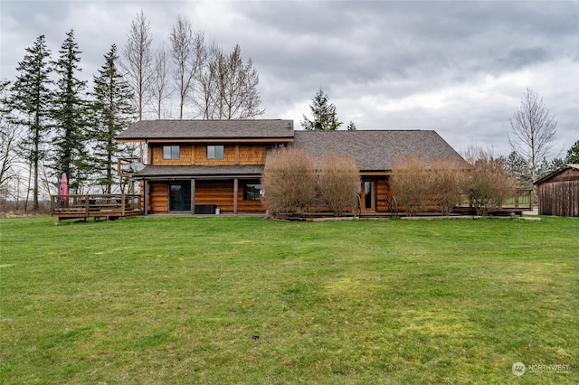 rear view of property featuring a wooden deck and a lawn