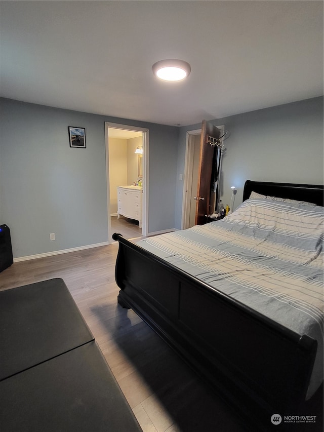 bedroom featuring light wood-type flooring and ensuite bathroom