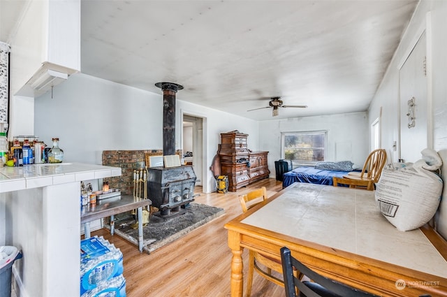 bedroom featuring light hardwood / wood-style floors, ceiling fan, and a wood stove