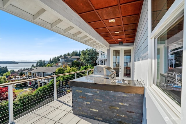 exterior space featuring sink, grilling area, exterior kitchen, and a water view