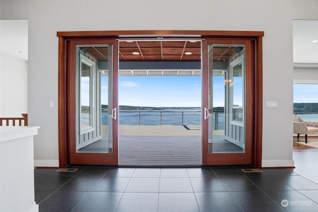 doorway to outside featuring a water view, dark tile patterned flooring, and french doors