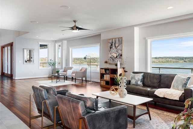 living room featuring hardwood / wood-style flooring, a water view, and ceiling fan