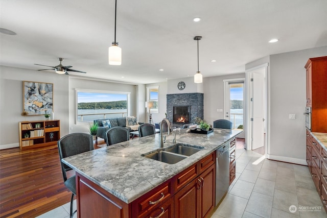 kitchen featuring appliances with stainless steel finishes, an island with sink, sink, a breakfast bar area, and hanging light fixtures