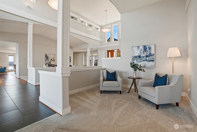 living area featuring ornate columns, carpet, and high vaulted ceiling