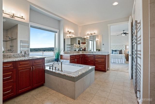 bathroom with a water view, vanity, a relaxing tiled tub, ceiling fan, and tile patterned flooring