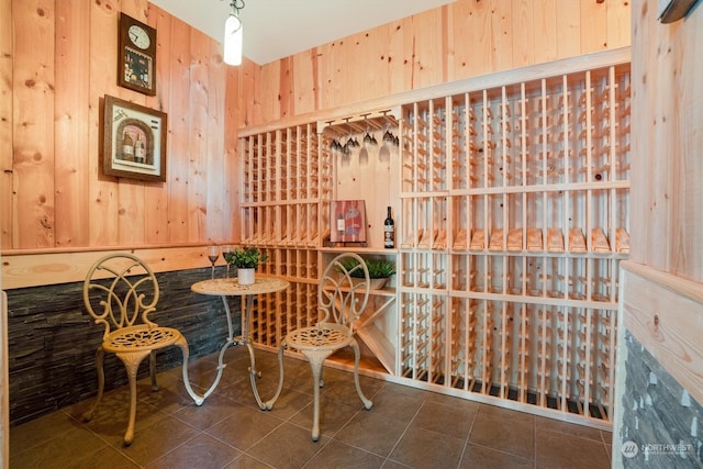 wine room featuring dark tile patterned floors and wood walls