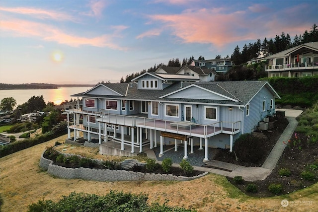 back house at dusk featuring a water view and central air condition unit