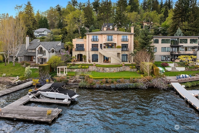 dock area featuring a balcony, a water view, and a yard