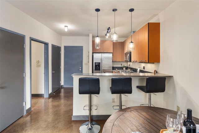 kitchen with appliances with stainless steel finishes, hanging light fixtures, kitchen peninsula, and a kitchen breakfast bar