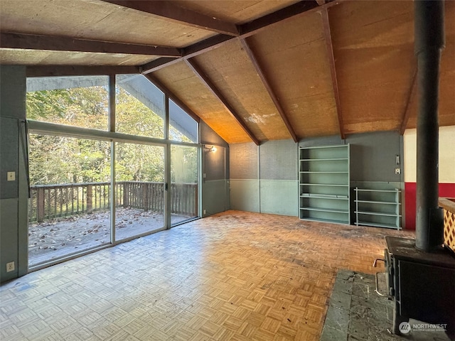 unfurnished living room with parquet flooring, a wood stove, and lofted ceiling with beams