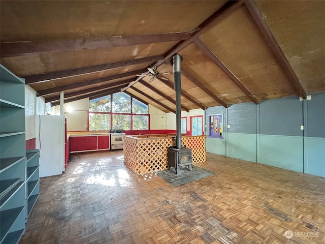 interior space with ceiling fan, lofted ceiling with beams, and a wood stove