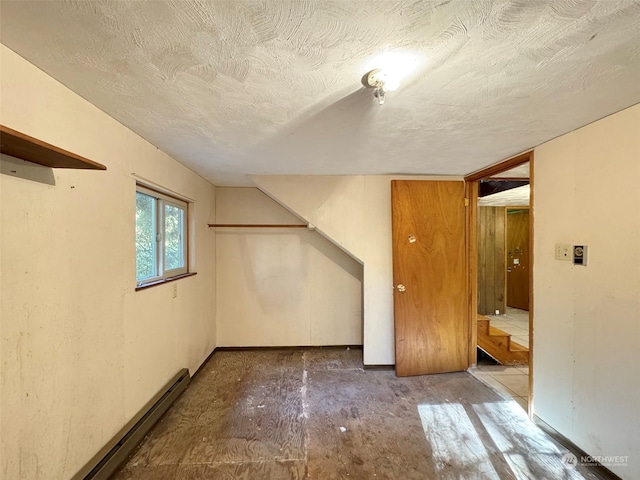 additional living space with a baseboard heating unit and a textured ceiling