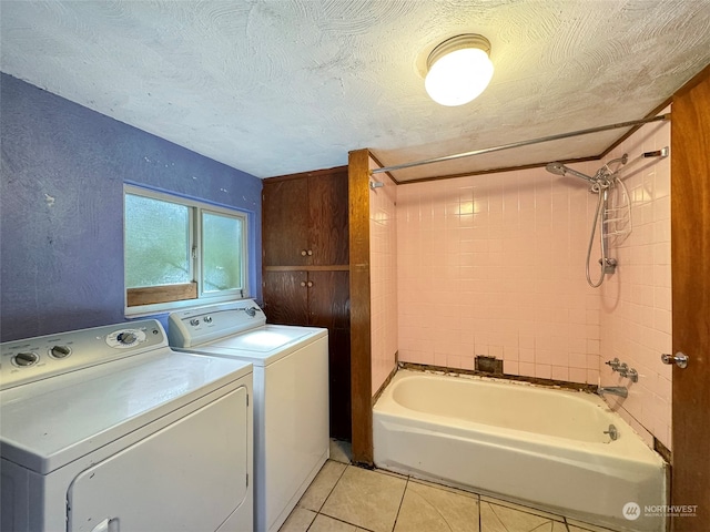 clothes washing area with a textured ceiling, wood walls, light tile patterned floors, and washer and clothes dryer