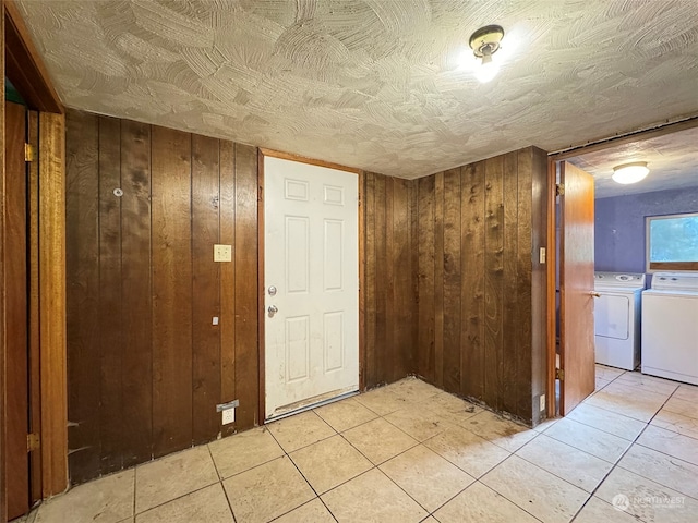 interior space featuring washing machine and clothes dryer, light tile patterned floors, and wooden walls