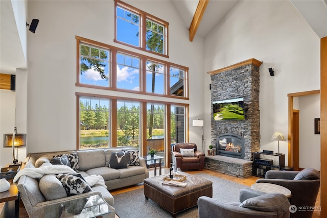 living room featuring wood-type flooring, a fireplace, beamed ceiling, and high vaulted ceiling