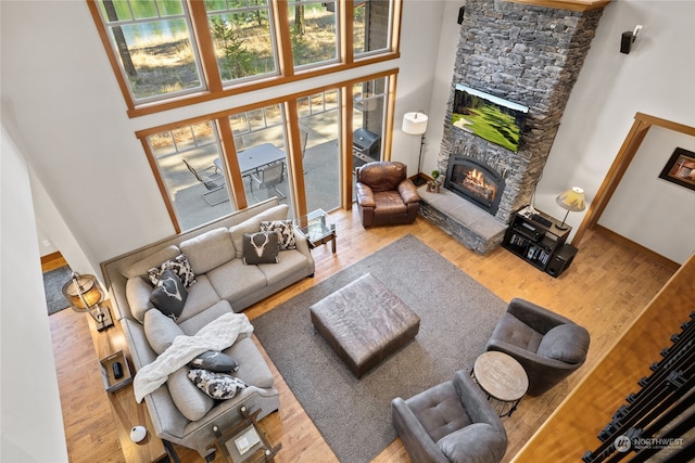 living room featuring a fireplace, a towering ceiling, and hardwood / wood-style flooring