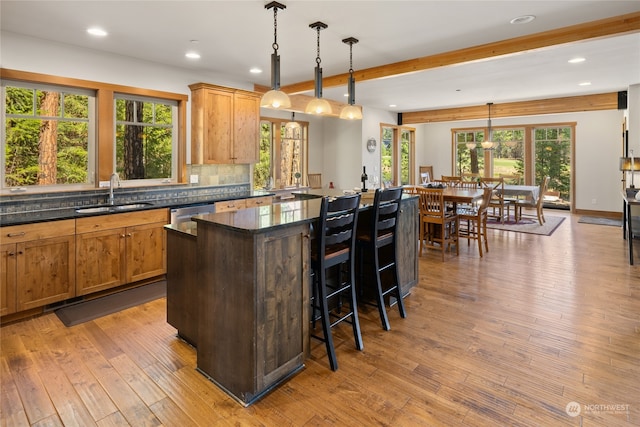 kitchen with light hardwood / wood-style floors, a center island, hanging light fixtures, and sink