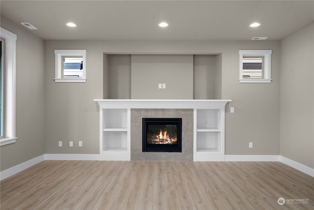 unfurnished living room featuring light wood-type flooring and a tile fireplace