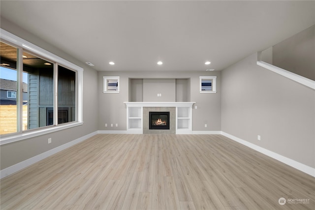 unfurnished living room featuring a tiled fireplace and light hardwood / wood-style floors