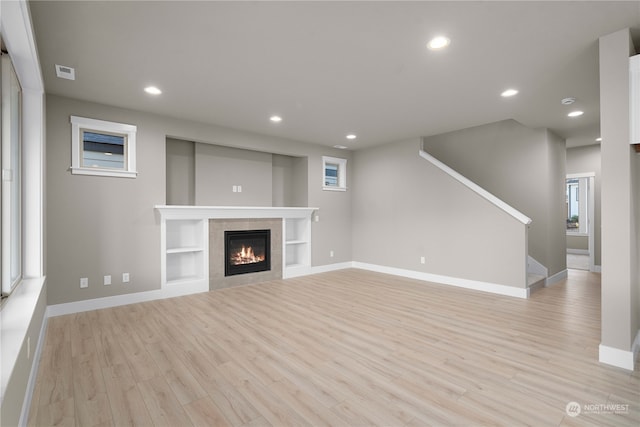 unfurnished living room featuring light hardwood / wood-style floors and a tiled fireplace