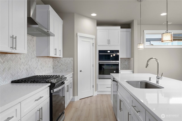 kitchen featuring wall chimney range hood, white cabinetry, and appliances with stainless steel finishes