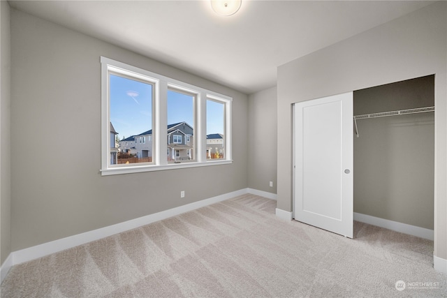 unfurnished bedroom with light colored carpet and a closet