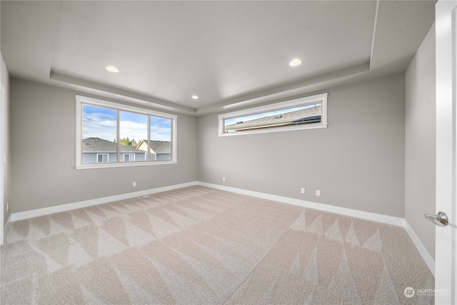 carpeted empty room with a tray ceiling