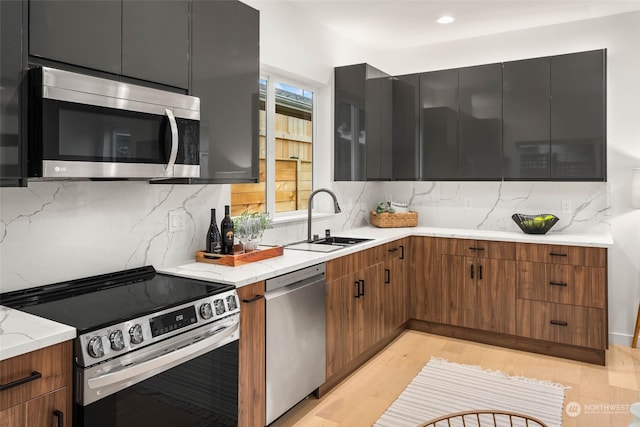 kitchen with sink, stainless steel appliances, light hardwood / wood-style floors, and tasteful backsplash