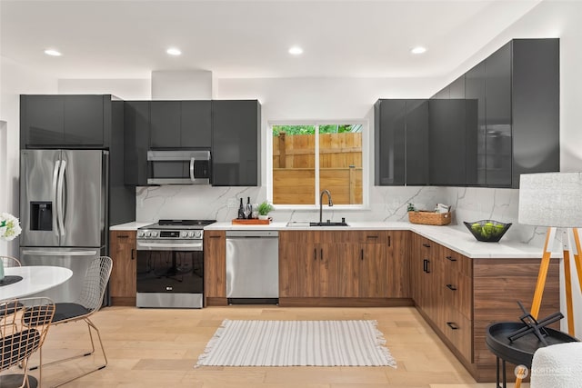 kitchen featuring appliances with stainless steel finishes, decorative backsplash, sink, and light hardwood / wood-style floors