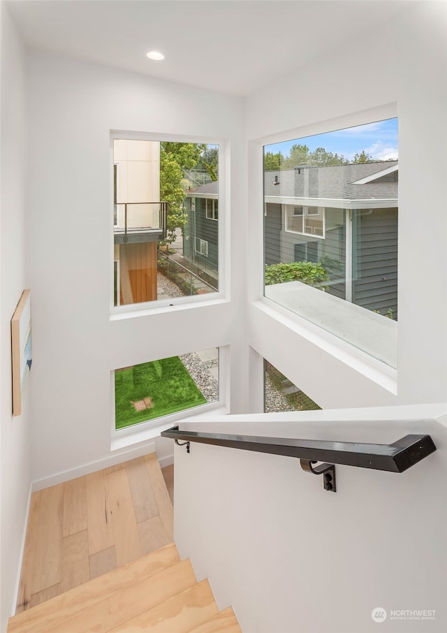 stairway featuring a wealth of natural light and hardwood / wood-style floors